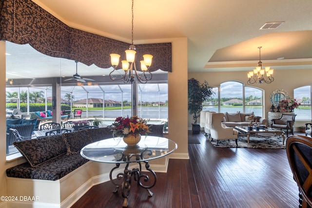 dining area featuring dark hardwood / wood-style floors, a water view, and ceiling fan with notable chandelier