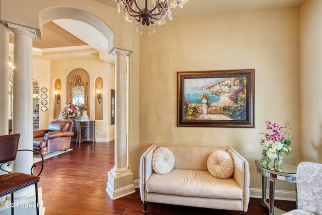 living area with dark hardwood / wood-style floors, a chandelier, and decorative columns