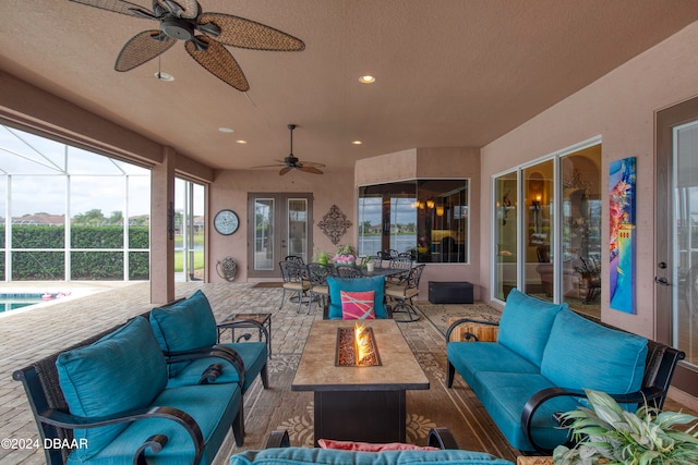 view of patio with an outdoor living space with a fire pit, glass enclosure, and ceiling fan