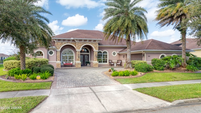 mediterranean / spanish home with a garage, french doors, and a front lawn