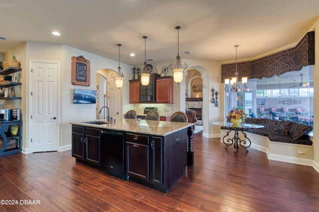 kitchen with dark hardwood / wood-style flooring, sink, black dishwasher, and a center island with sink