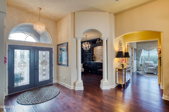 foyer featuring french doors, an inviting chandelier, decorative columns, high vaulted ceiling, and dark hardwood / wood-style floors