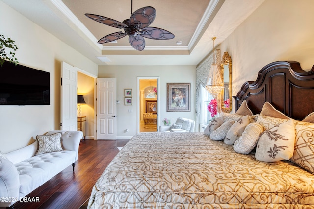 bedroom with ensuite bath, ornamental molding, dark hardwood / wood-style floors, ceiling fan, and a tray ceiling