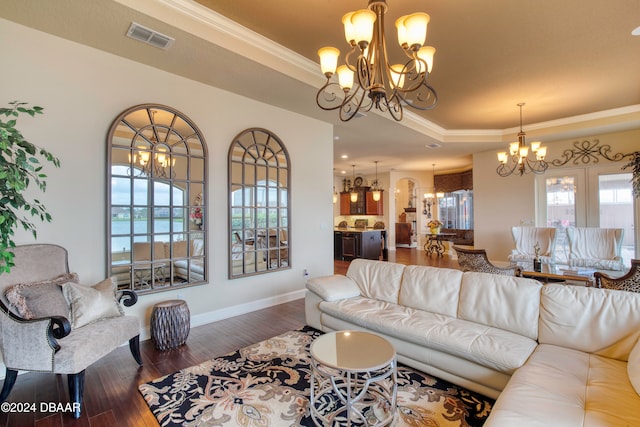 living room featuring ornamental molding, dark wood-type flooring, a chandelier, and a tray ceiling