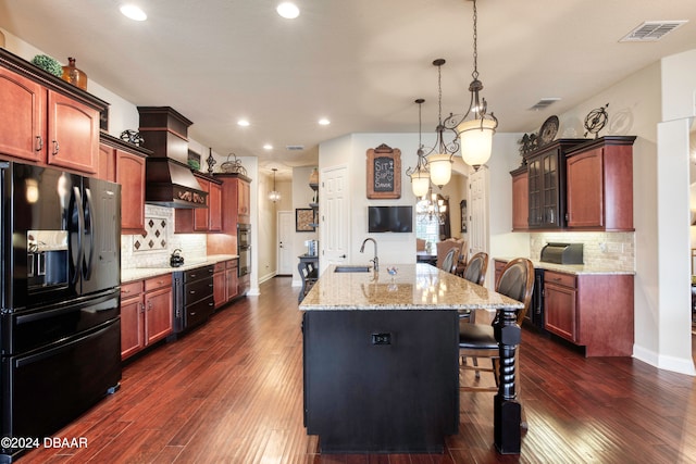 kitchen featuring black appliances, custom range hood, dark hardwood / wood-style floors, a breakfast bar area, and a kitchen island with sink