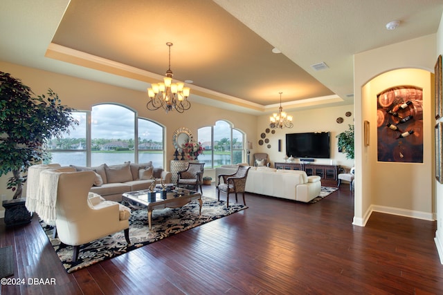 living room featuring a chandelier, a tray ceiling, and dark hardwood / wood-style floors