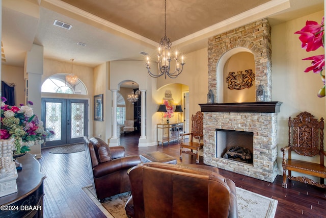 living room featuring dark hardwood / wood-style floors, a stone fireplace, french doors, and ornamental molding