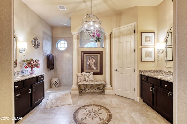 bathroom with a tile shower, a chandelier, vanity, tile patterned floors, and ornate columns