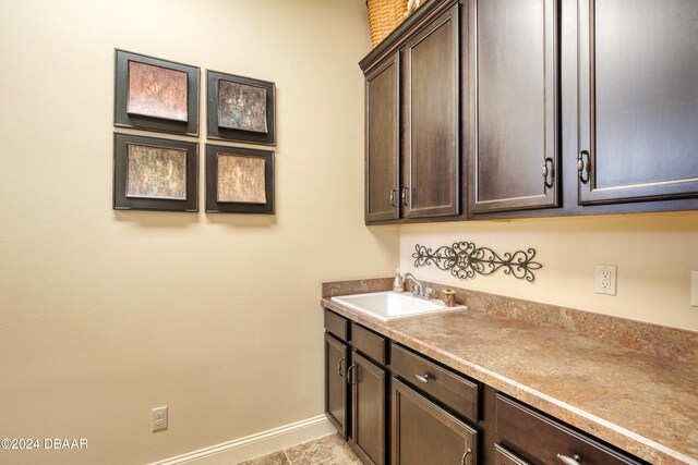 kitchen featuring sink, dark brown cabinets, and light tile patterned floors