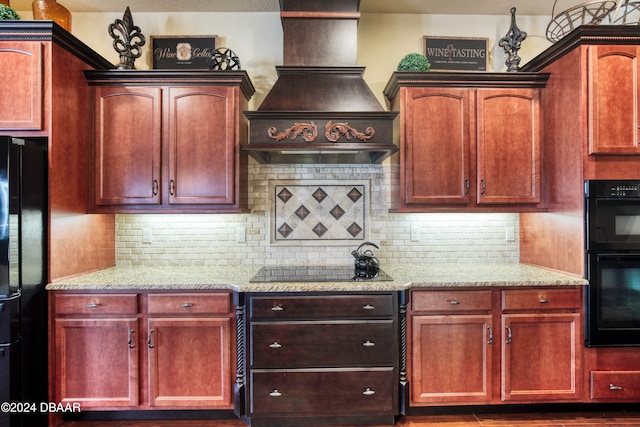 kitchen with custom range hood, black appliances, light stone counters, and tasteful backsplash