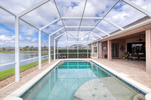 view of pool with a patio, a water view, and glass enclosure