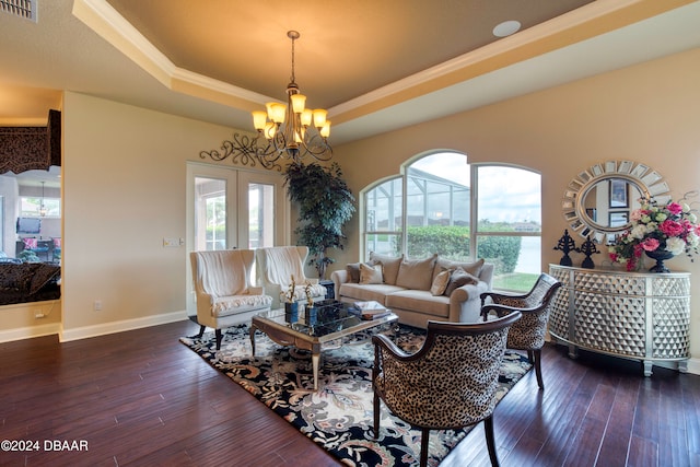 living room featuring dark hardwood / wood-style floors, a raised ceiling, and an inviting chandelier