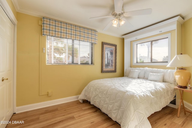 bedroom with a closet, ceiling fan, crown molding, and light wood-type flooring