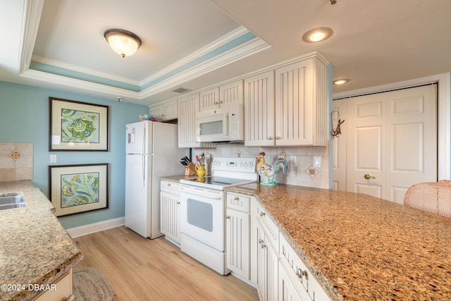 kitchen with backsplash, light stone counters, white appliances, a tray ceiling, and light hardwood / wood-style floors