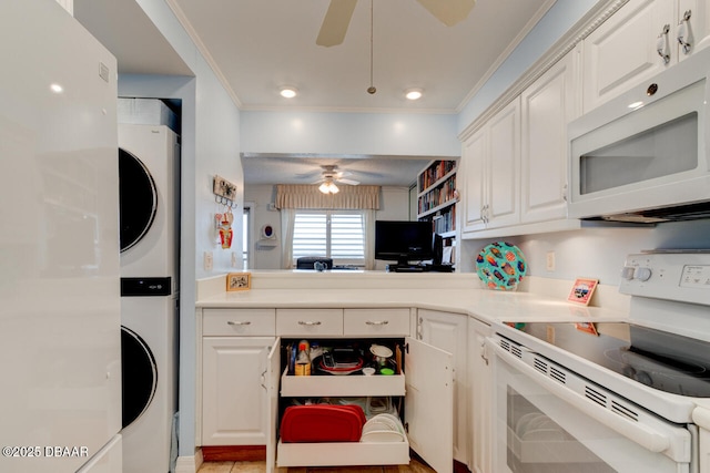 kitchen with stacked washer / drying machine, light countertops, ornamental molding, white cabinetry, and white appliances