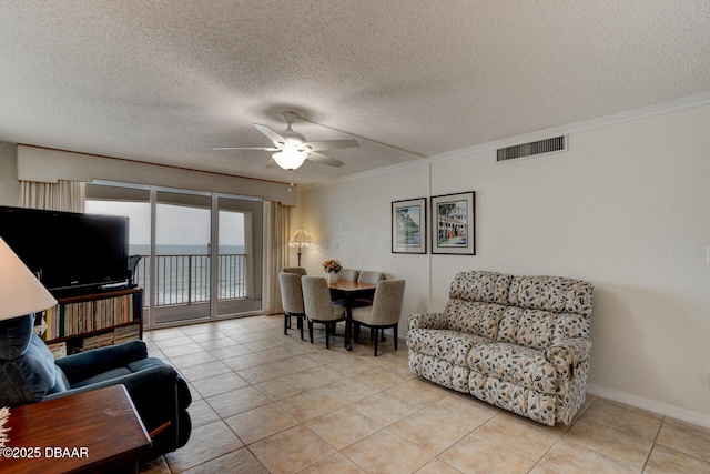 living area featuring light tile patterned floors, visible vents, ornamental molding, a ceiling fan, and a textured ceiling