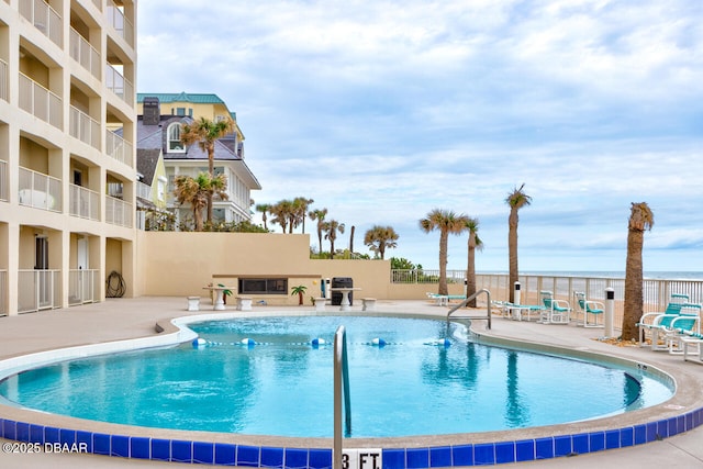 pool with a patio area and fence