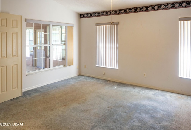 carpeted spare room with vaulted ceiling