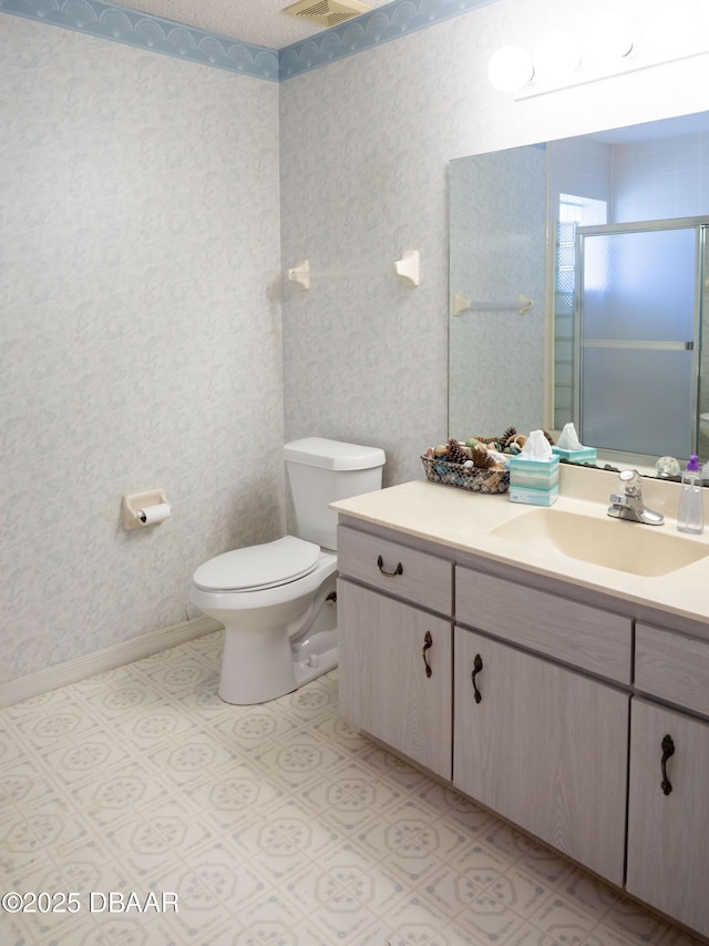 bathroom with vanity, a shower with shower door, and toilet