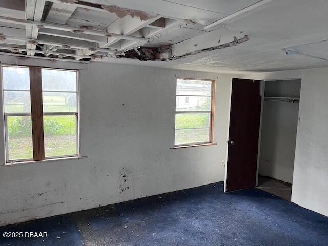 unfurnished bedroom with multiple windows and concrete flooring