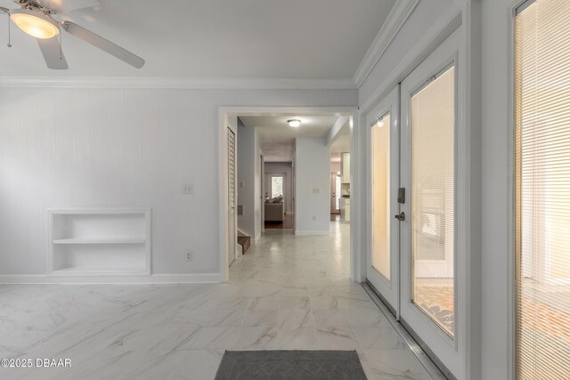 corridor with built in shelves, light marble finish flooring, ornamental molding, and baseboards