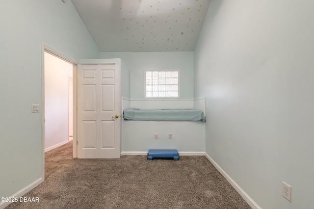 carpeted spare room featuring vaulted ceiling and baseboards