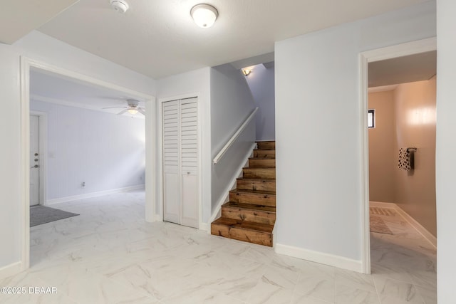 stairs with marble finish floors, ceiling fan, and baseboards