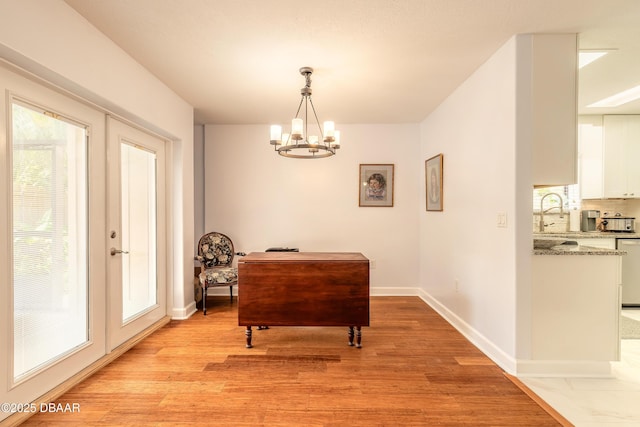 dining area featuring a chandelier, light wood-style floors, plenty of natural light, and baseboards