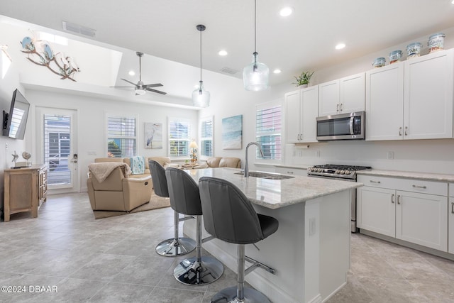 kitchen featuring white cabinetry, stainless steel appliances, and an island with sink