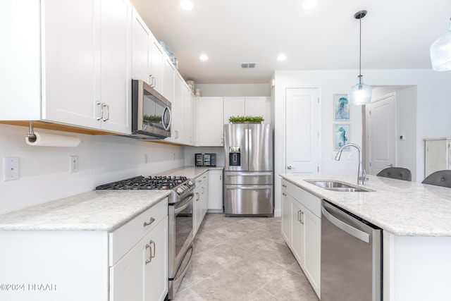 kitchen featuring white cabinetry, sink, hanging light fixtures, stainless steel appliances, and an island with sink