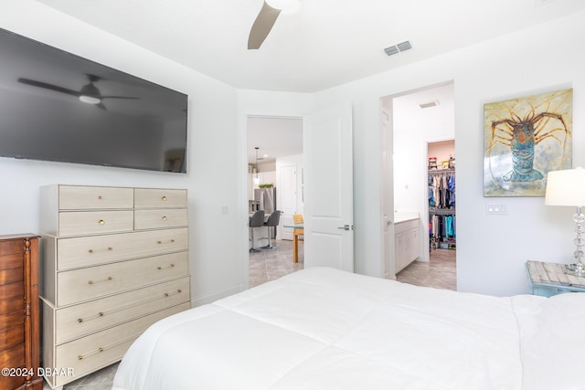 bedroom with a walk in closet, ensuite bathroom, ceiling fan, light tile patterned floors, and a closet