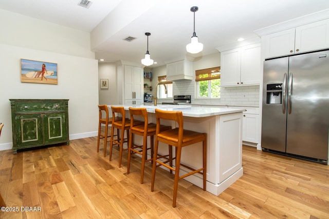1327 Wayne Ave, New Smyrna Beach, FL 32168 - kitchen with stainless steel fridge with ice dispenser, light countertops, light wood-style flooring, tasteful backsplash, and white cabinets