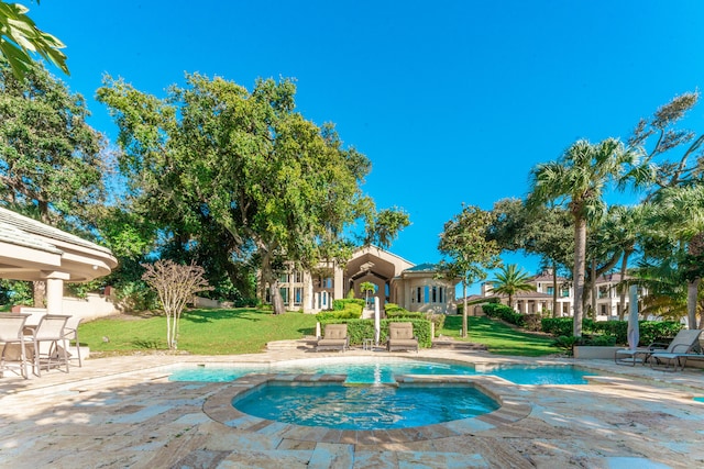 view of pool with a lawn, a patio, and an in ground hot tub