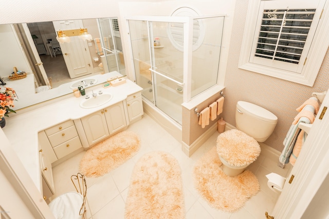 full bathroom featuring toilet, bath / shower combo with glass door, vanity, and tile patterned floors