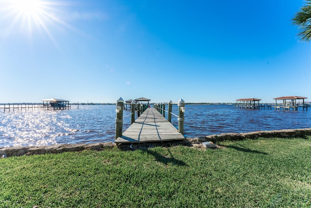 view of dock with a yard and a water view