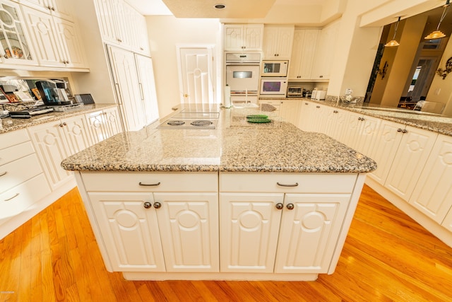 kitchen featuring electric cooktop, light hardwood / wood-style flooring, white microwave, and light stone counters