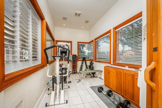 workout room featuring light tile patterned flooring and a textured ceiling