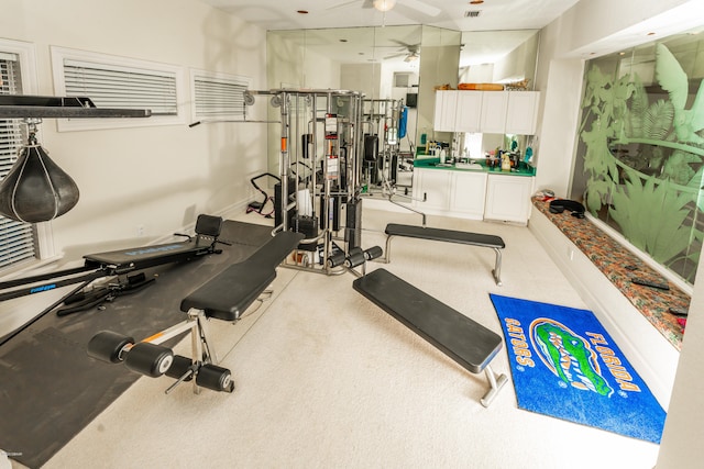 workout room with ceiling fan and light carpet