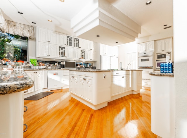 kitchen with white cabinetry, light hardwood / wood-style flooring, white appliances, and stone countertops