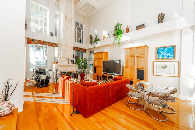 living room featuring a towering ceiling, beamed ceiling, and light hardwood / wood-style flooring