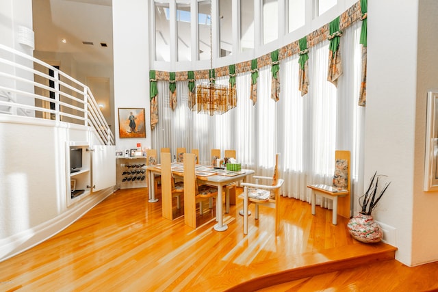 dining room featuring a high ceiling, wood-type flooring, and a chandelier