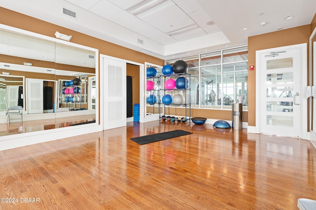 exercise area with hardwood / wood-style floors and a raised ceiling