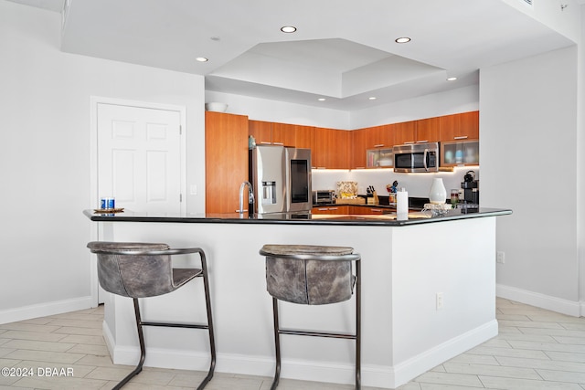 kitchen with a kitchen bar, appliances with stainless steel finishes, sink, and a raised ceiling