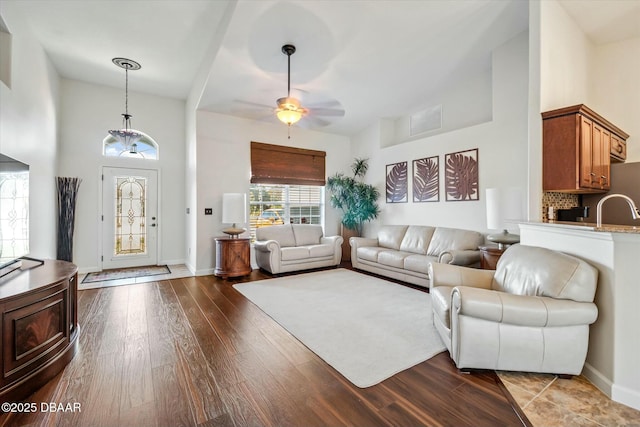 living room featuring ceiling fan, sink, light hardwood / wood-style flooring, and a high ceiling