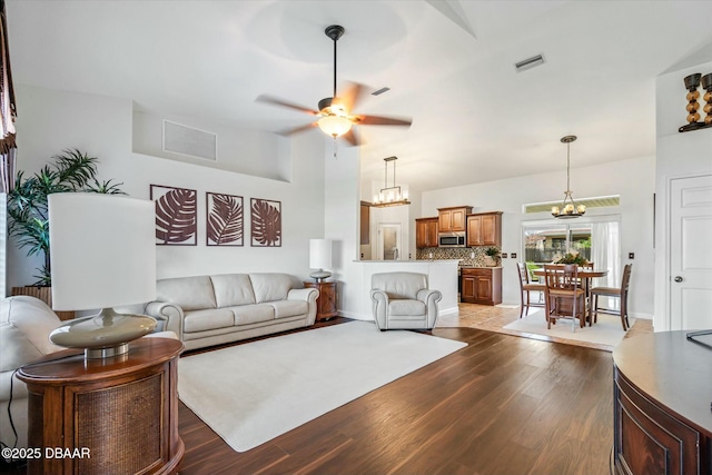 living room featuring ceiling fan with notable chandelier and hardwood / wood-style floors