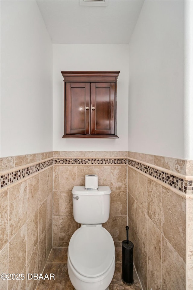 bathroom with tile walls and toilet