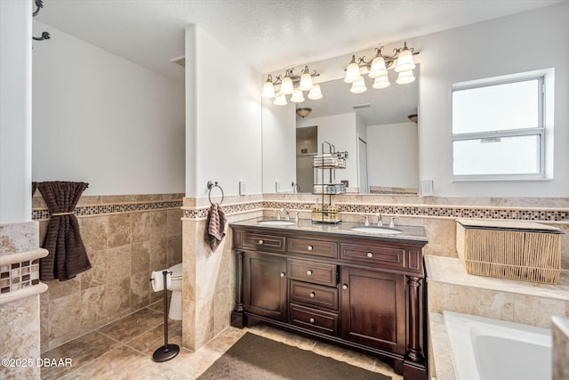 bathroom featuring tile walls, vanity, tile patterned floors, and a tub