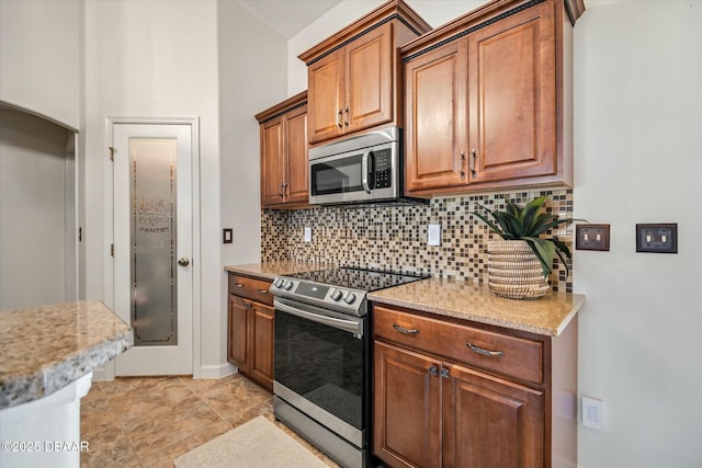 kitchen with light stone counters, stainless steel appliances, and decorative backsplash