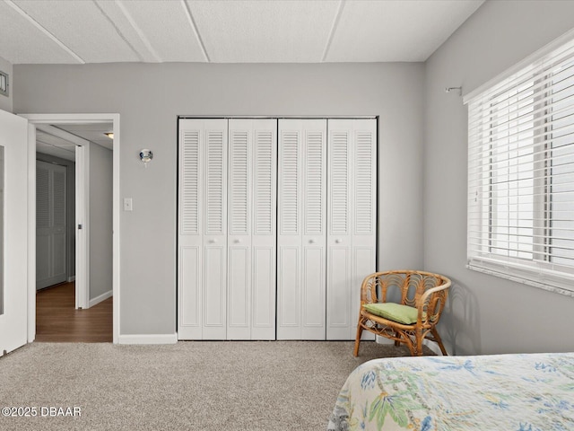carpeted bedroom with a closet and baseboards