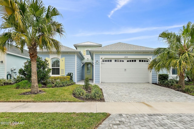 view of front of house with a garage, decorative driveway, and a front lawn